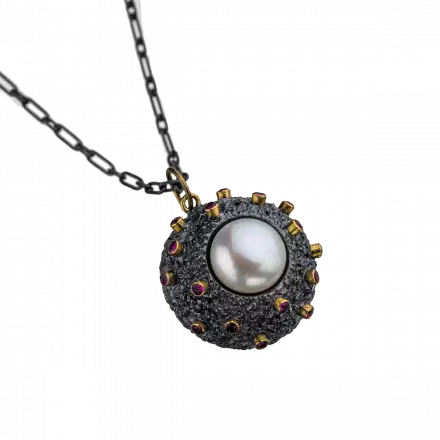 Silver Necklace with round pendant mounted with center white pearl surrounded by rubies in 18k gold leaf settings